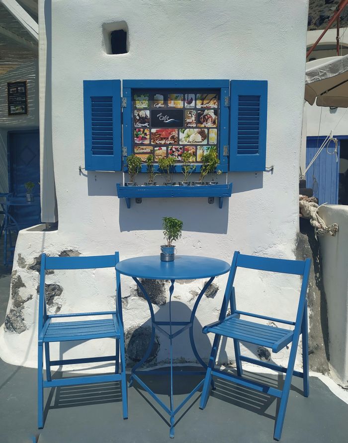 A picturesque blue café table and chairs set against a white wall exterior, perfect for outdoor dining.