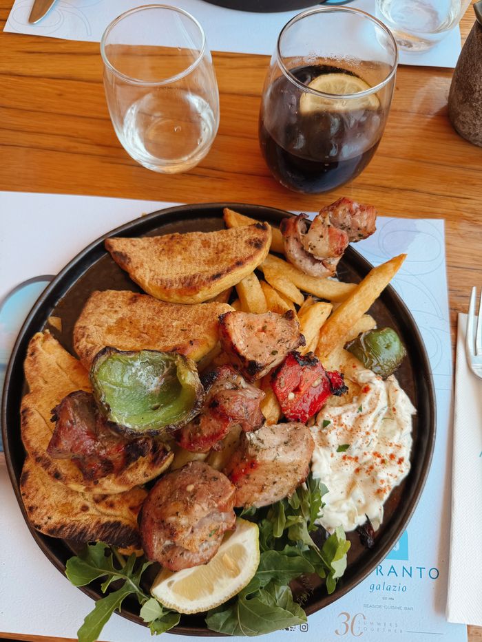 Delicious Greek souvlaki with tzatziki, served with roasted vegetables and wedges.